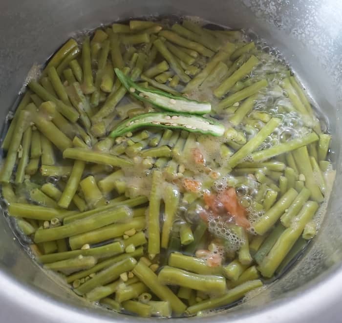 When the long beans are cooked, add 1-2 slit green chilies and 1-2 teaspoons of jaggery. Bring this to a boil.