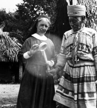 Deaconess Harriet Bedell with a cypress-wood sofkee spoon, with Doctor Tiger in a Seminole camp in 1936.