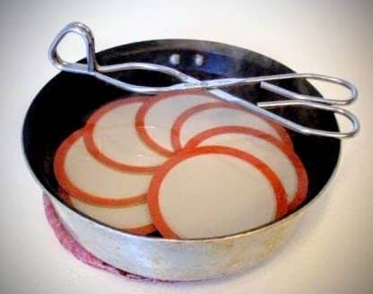 Set lids in a small pan and pour scalding water over them, or simmer them slowly in a saucepan of water. DO NOT BOIL! Leave them in the water until you use them, so they remain warm with softened rubber rings.