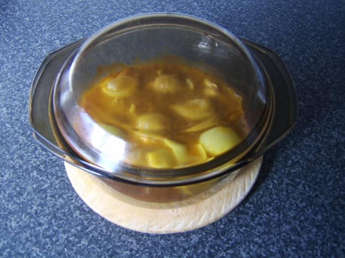 The chicken drumstick curry casserole is taken from the oven and set aside to rest while the rice is prepared