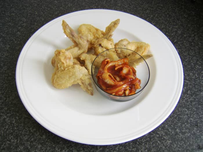 The spiced onions are added to a small dish and plated with the deep fried chicken wings clustered around it
