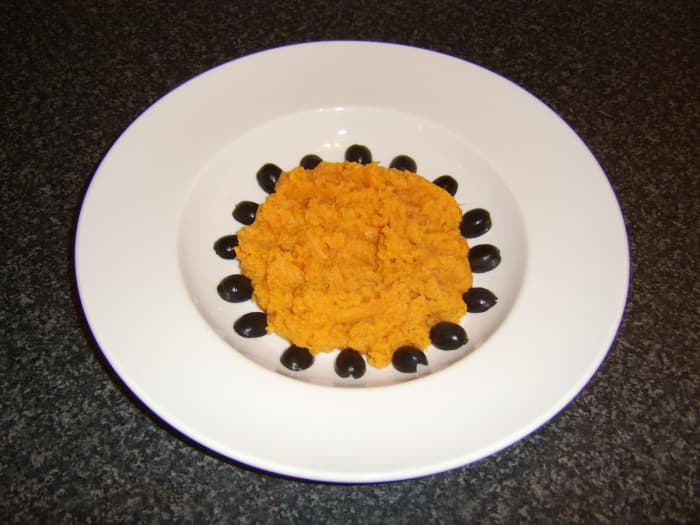 The sweet potato is piled in the centre of the plate and surrounded by the pitted and halved black olives