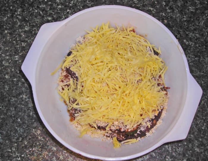 Stuffed eggplant sprinkled with breadcrumbs and grated cheese, ready to be baked for 20 minutes.