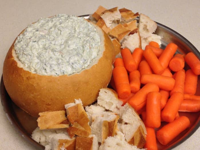 Spinach Dip made with Knorr dry vegetable soup mix. Served in a sourdough bread bowl with bread and carrots.