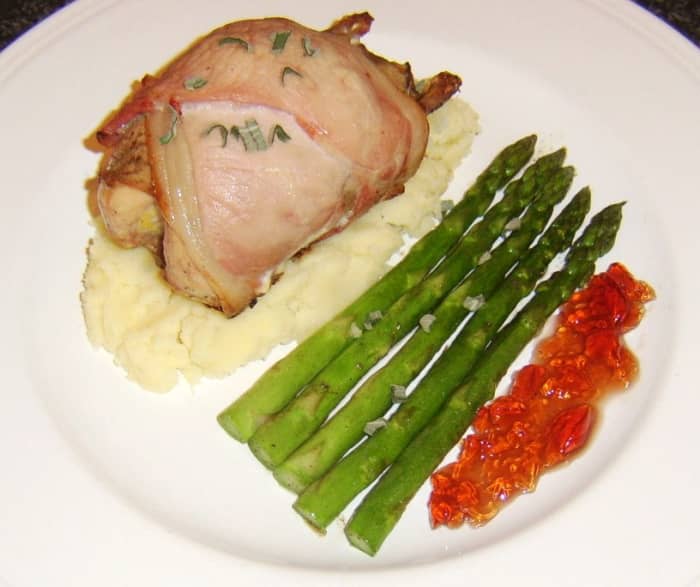 Whole partridge wrapped in bacon and roasted is served on a bed of Dijon mustard mash, with sauteed asparagus and redcurrant sauce