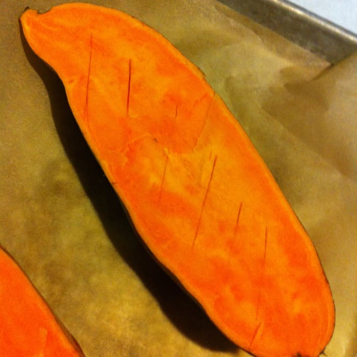 A sweet potato before cooking: the interior flesh has been scored in order to expose more of its surface area to heat while roasting.