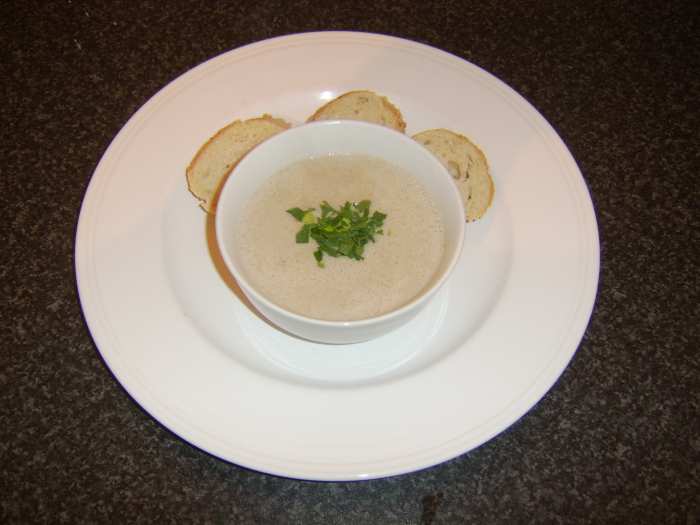 Cream of chestnut and roast duck soup is served garnished with a little parsley and with some crusty bread on the side