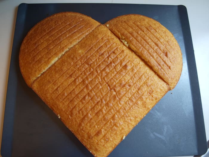 Using a large tray, assemble the unfrosted cake. Place the square cake on the diagonal and place the two halves of the circular cake at the top left and right. The heart shape is formed.