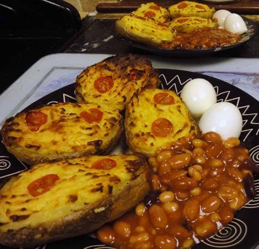 Stuffed potato jackets with potato cheese and onion sauce served with hardboiled egg and baked beans