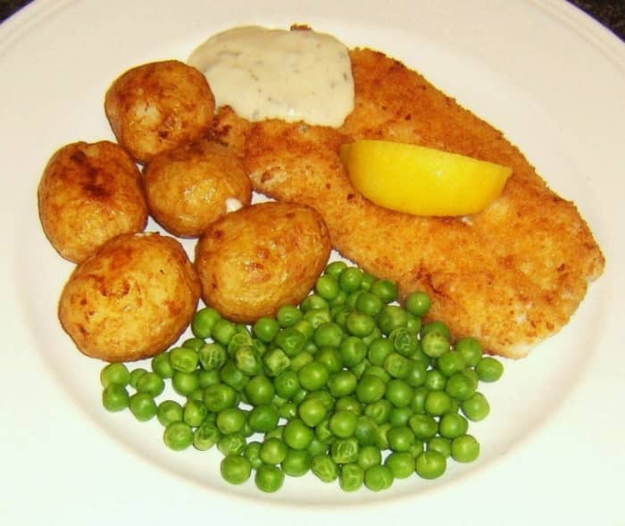 Breaded haddock fillet is shallow fried before being served with roast potatoes, peas and tartare sauce