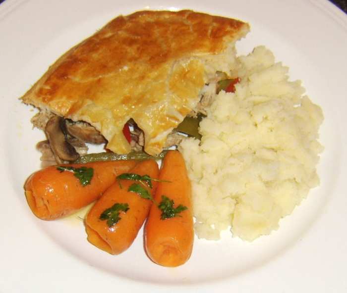 Rabbit and pork pie with bell peppers and mushrooms is served with mashed potatoes and Chantenay carrots