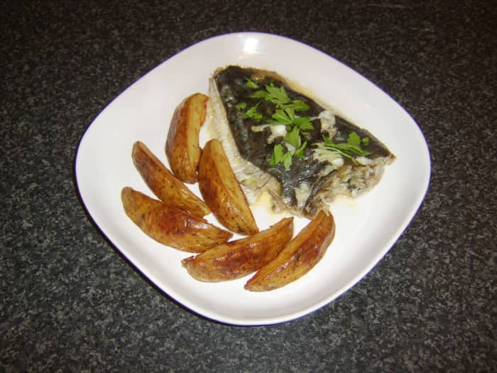 A whole, prepared flounder is baked with some subtle flavourings before being served wimply with deep fried potato wedges