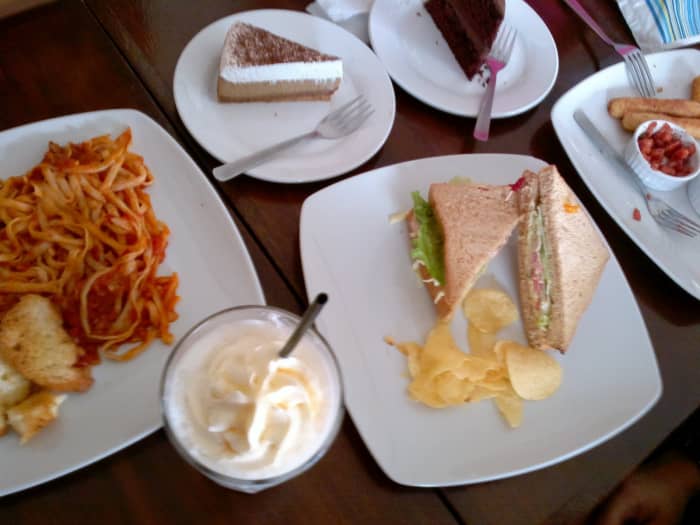 A spread of food at Cafe Cristina—clockwise: cappuccino cheesecake, chocolate cake, tuna and crab sandwich, chocolate milkshake, and tuna and tomato pasta.