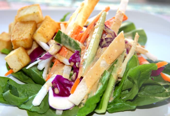 Thai almond dressing over a tofu vegetarian salad with jicama, carrots, cabbage, cucumbers, and spinach