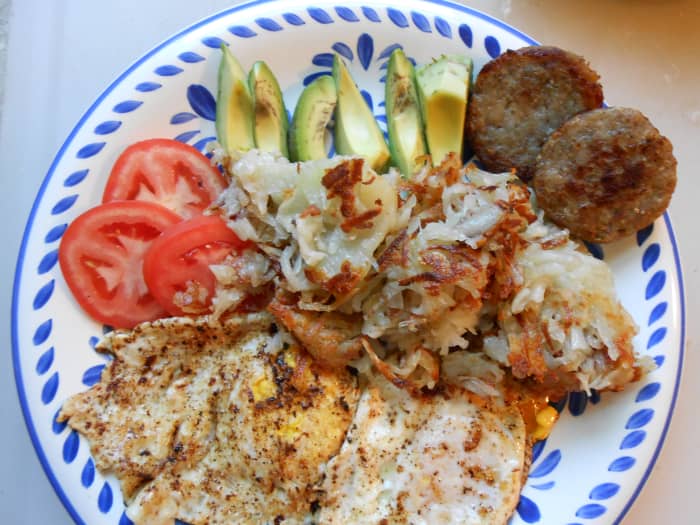 A "wood cutter's breakfast:" 2 eggs, hash browns, sausage served with sliced avocado and tomato.