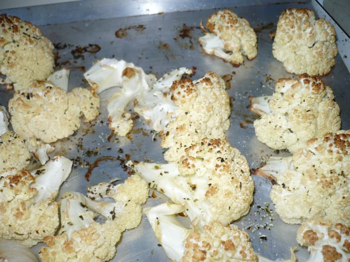 Take the garlic and cauliflower out of the oven and squeeze out the individual cloves of garlic on a plate.