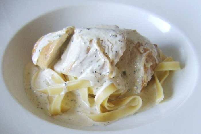 Sliced roast chicken breast is served on a bed of tagliatelle with a garlic and peppercorn cream sauce