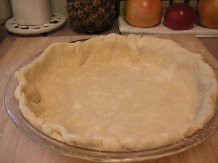 Using scissors or a knife, trim off the excess dough leaving about half an inch over the edges. Fold under the excess to form a rim along the outside.