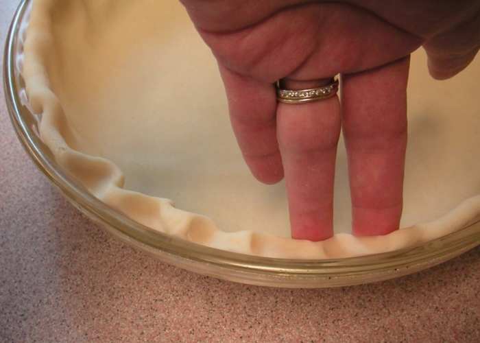 Use two fingers of one hand, pushing a finger from the other hand between them to form the fluted edge of the crust.