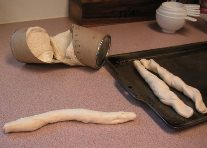 Separate the biscuits and roll between the palms to elongate. Press the ends down on the baking sheet to secure them.