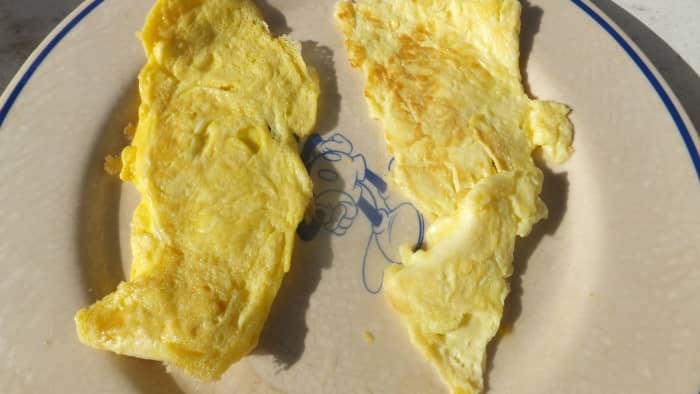 The farm fresh egg on the left side is darker golden color than the paler yellow supermarket egg on the right side.
