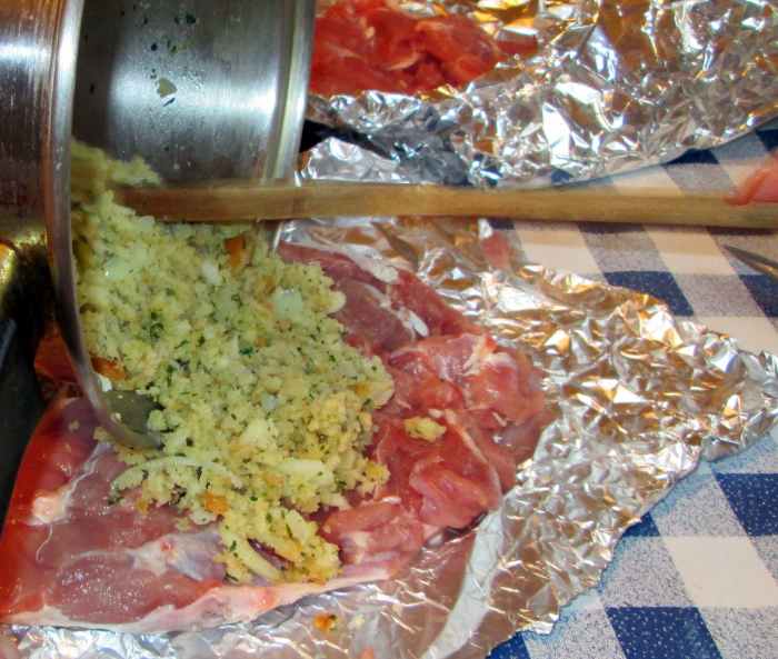 Adding the stuffing to the turkey meat on the tinfoil.