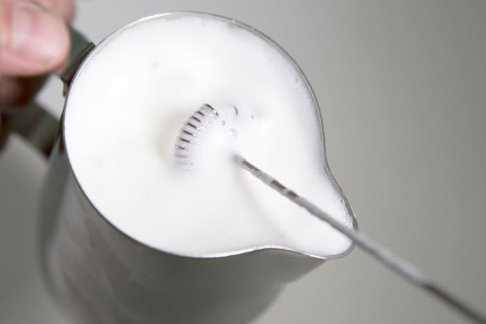 Milk can be frothed using a hand held frother, or by using an electric frother pitcher. Hand held frothers are cheap and easy to use and work through a little propeller bubbling up the milk.