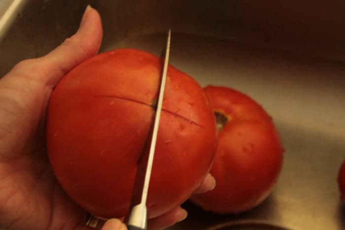 Score the bottom of the tomato prior to blanching so that the peel will easily pull away.