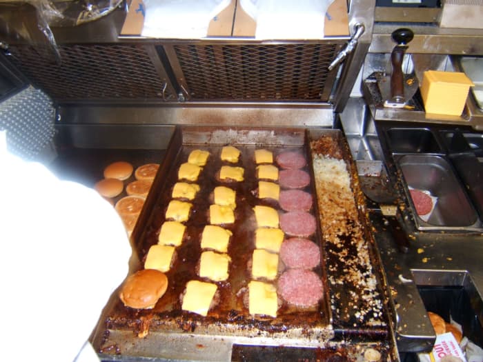 I'm not sure how an associate got away with taking this photo, but here's the grill. Looks like the cook is having a busy day; that's a lot of cheeseburgers and double-doubles! You can also see grilled onions being cooked on the right.