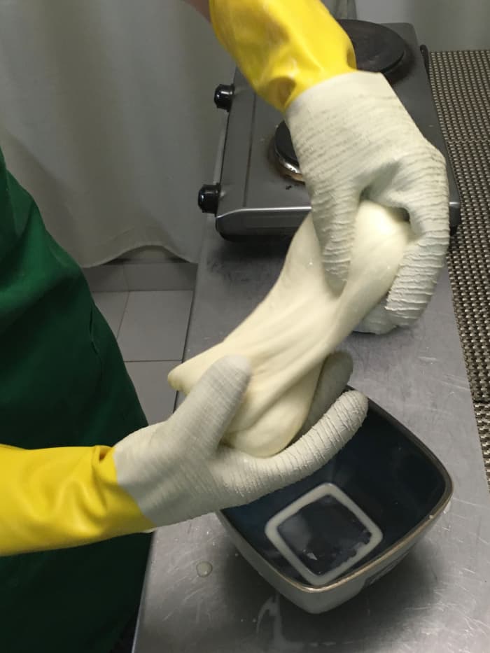 Stretch and pull the cheese, like taffy. Be gentle. More whey will drain off.