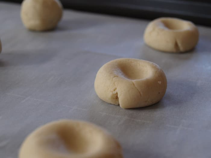 Form 1-inch balls and place them on a prepared baking sheet. Make an indent with your thumb.