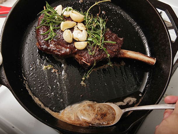 Throw the garlic, thyme, and rosemary into the butter and begin to spoon the butter over the steak, occasionally resting the herbs on top of the steak as well.
