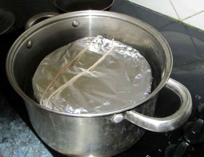 Carefully lift the pudding bowl by the string handle and place it in the pan for steaming.