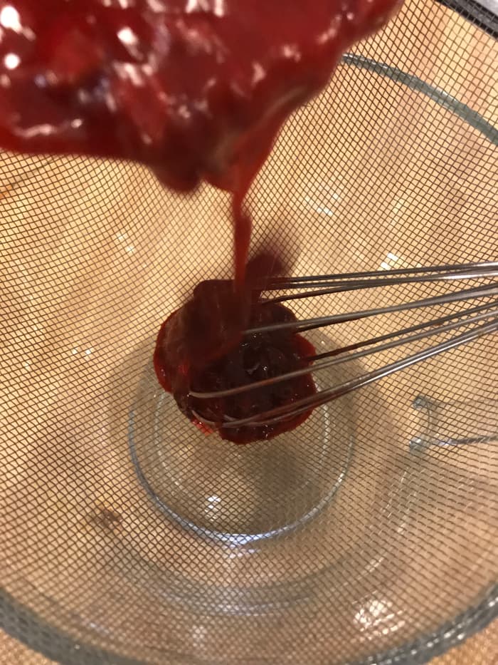 Strain the sauce through a fine meshed strainer to remove the leftover solids. This will get the seeds and pulp both, leaving the sauce clear and glossy - it's beautiful!