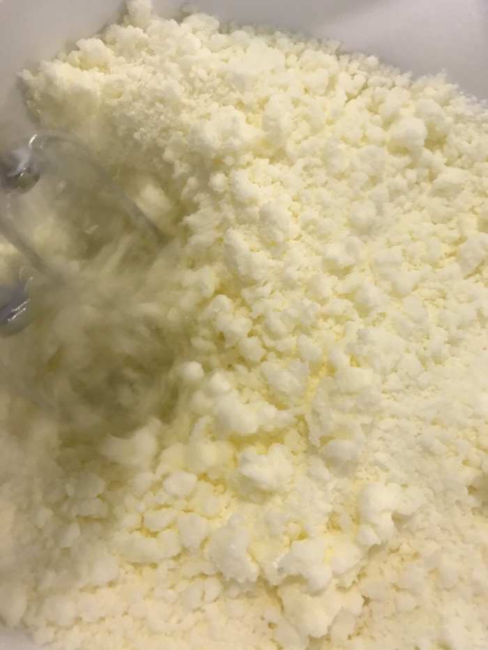 Beat together the butter and powdered sugar until the mixture is light and fluffy. It will almost resemble coarse sand, and you shouldn't see any obvious lumps of butter. Beating well at this stage helps ensure the finished frosting is super smooth.