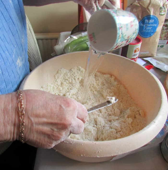 Make a hole in the middle and pour in half the water. Gradually stir the water around the mixture.