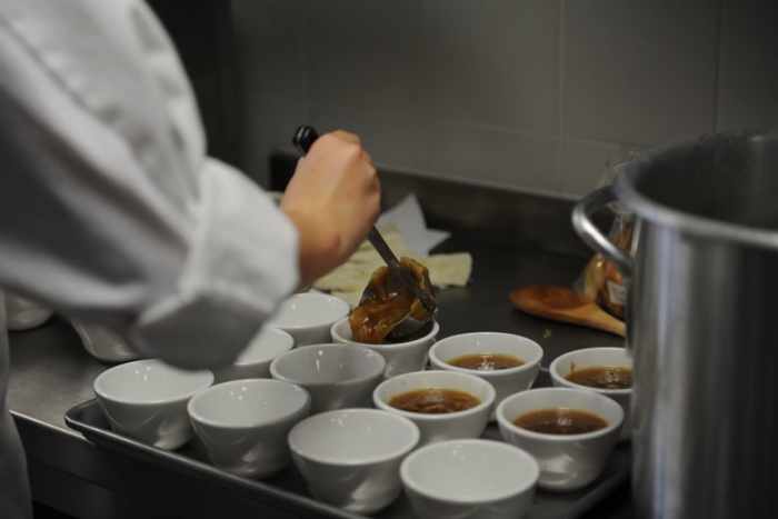 a chef ladling soup into bowls