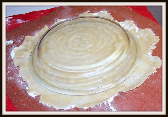 My favorite way for a bottom crust is to place the pie plate, topside down, upon the rolled out crust. That is the easiest way to center it. Then flip it over. Here I have used a glass plate for ease of seeing what to do.
