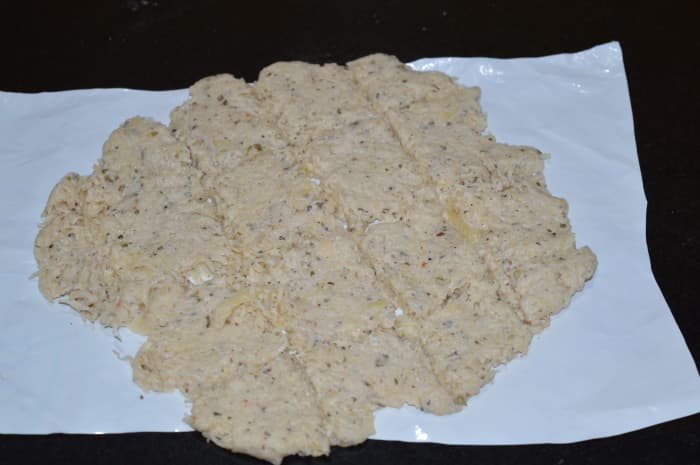 Step seven: Place the dough between two plastic sheets or butter papers. Press the dough and roll using a rolling pin to make it thin and flat. Remove the upside sheet. Cut it in square shapes.