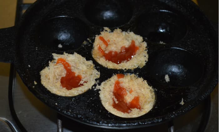 Step four: Place each slice with the butter portion touching the pan. Gently press it on all sides to give it a cup shape. Add some pizza sauce into all the cups.