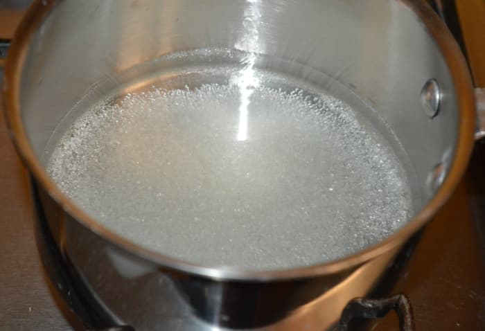 Step one: To make the sugar syrup, add water to a saucepan as per instructions. Add sugar to it. Boil the mixture until it thickens a bit. Throw in cardamom powder. Turn off the heat. Cover it partially.