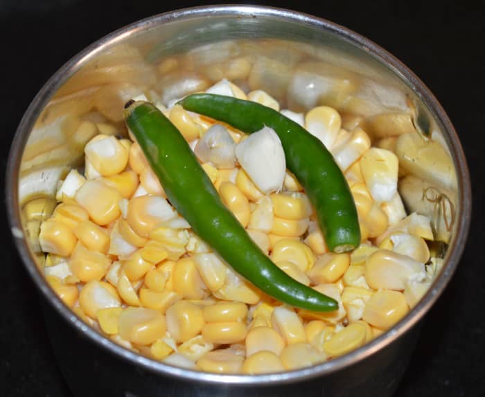 Step one: Grind corn kernels, green chilies, and garlic to get a coarse paste. Transfer the paste to a mixing bowl.