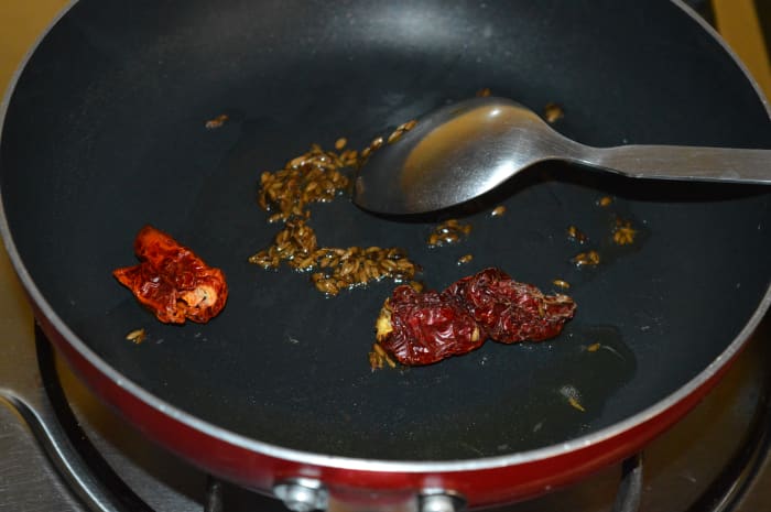 Step one: Heat half a teaspoon of ghee or oil in a deep-bottomed pan. Throw in cumin seeds and red chilies. Saute till cumin seeds sizzle.