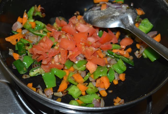 Step five: Add chopped tomatoes. Continue sauteing for two more minutes. Add grated coconut and chopped coriander leaves.