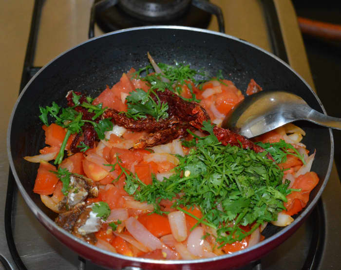 Step two: Add chopped coriander leaves, dry red chilies, tamarind, and remaining salt. Saute for one more minute. Turn off the heat. Keep aside for cooling.