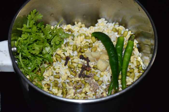 Step two: Strain the water. Put the beans, dal, and rice in a grinder or blender. Add green chilies, cloves, fresh coriander, chopped ginger, and salt. Grind, adding soaked water or fresh water to get a coarse or near-smooth batter.