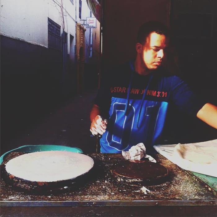 Preparing the waraq (papers). A man in the Rabat medina deftly transfers the raw filo dough to a hot circular griddle. These layers will be used to make flaky pastilla.