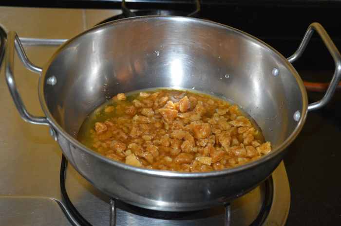 Step five: Add powdered jaggery to a thick-bottomed pan. Add 1/4 cup of water. Turn on the heat. Stir the mix for 5 to 6 minutes or until it becomes a bit thick and sticky.