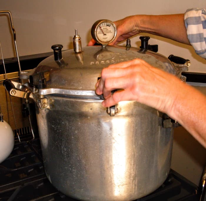Screw or fasten lid in place. On old-style canners, screw knobs down tightly in opposites, to achieve an even seal.