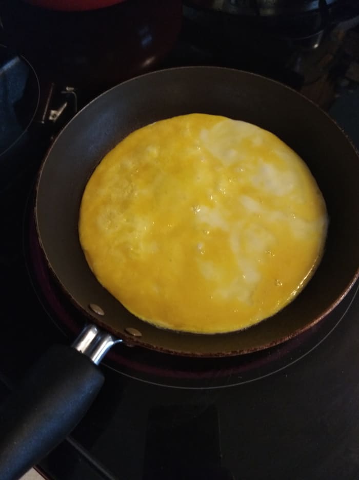 Get a small skillet and take 2 eggs and scramble them in a small bowl. Add salt and pepper if you wish. Heat the pan on medium-high and pour eggs into the pan with nonstick cooking spray. Let it sit until it gets solid on one side.